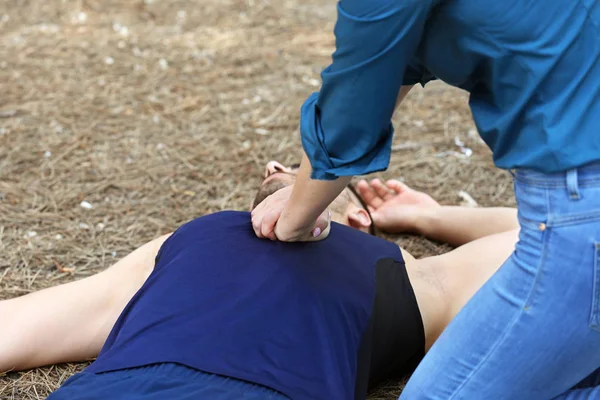 Woman giving CPR to unconscious man outdoors — Stock Photo, Image