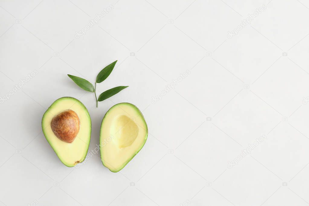 Halves of ripe avocado on white background