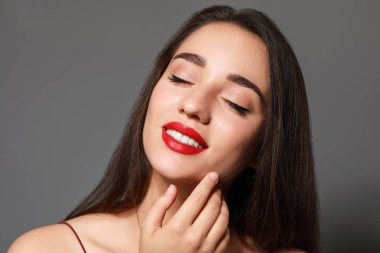 Gri arkaplanda parlak ruj izi olan güzel bir genç kadın.
