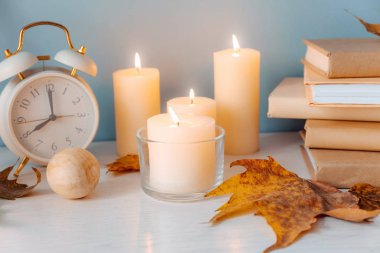 Güzel yanan mumlar, kitaplar, kuru sonbahar yaprakları ve renk duvara yakın dekor ile Tablo