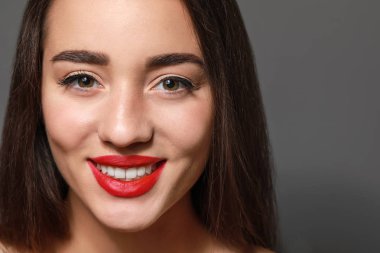 Gri arkaplanda parlak ruj izi olan güzel bir genç kadın.