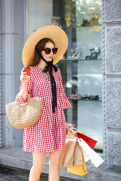 Stylische junge Frau mit Einkaufstaschen und Kaffee im Freien — Stockfoto