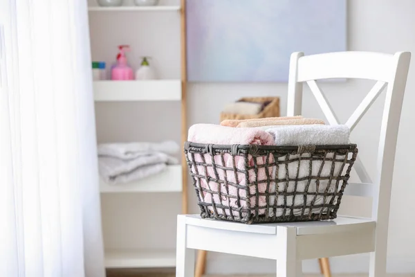 Cesta con toallas suaves limpias en la silla en el baño —  Fotos de Stock