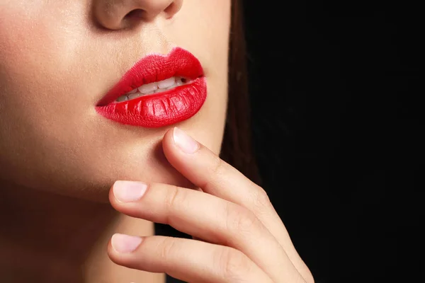 Belle jeune femme avec rouge à lèvres lumineux sur fond sombre, gros plan — Photo
