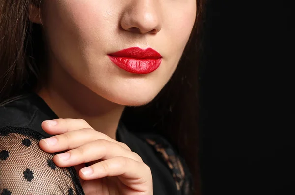 Beautiful young woman with bright lipstick on dark background, closeup — Stock Photo, Image