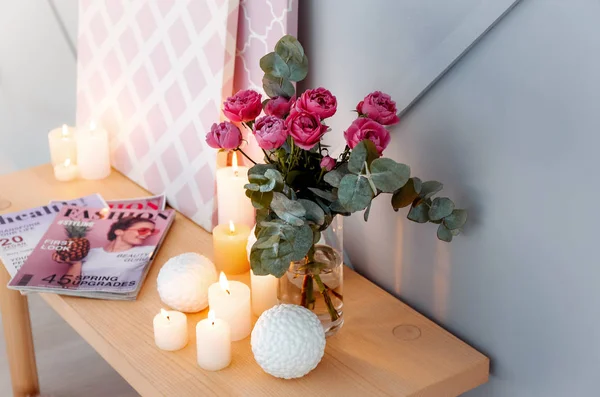 Beautiful burning candles and bouquet of flowers on table in room — Stock Photo, Image