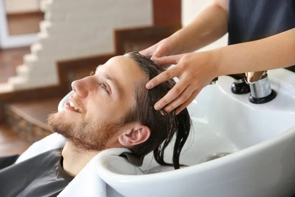 Vrouwelijke Kapper wassen haar van jonge man in salon — Stockfoto