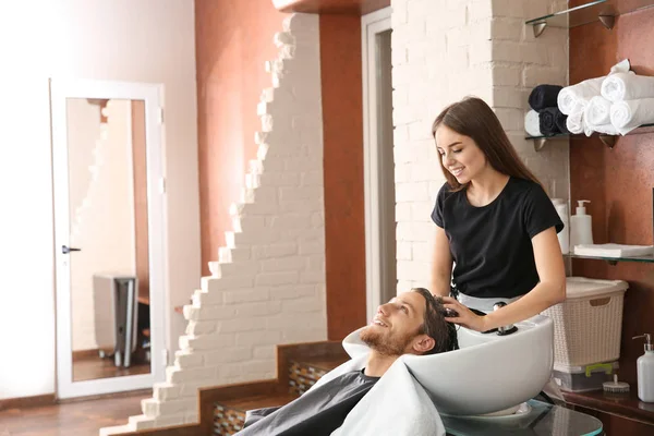 Femme coiffeuse laver les cheveux du jeune homme dans le salon — Photo