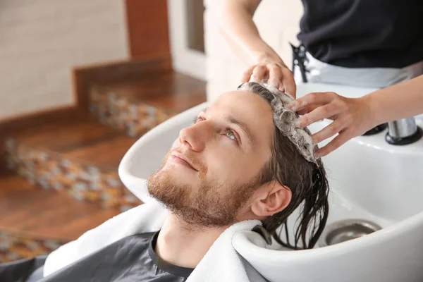 Female hairdresser washing hair of young man in salon — Stock Photo, Image