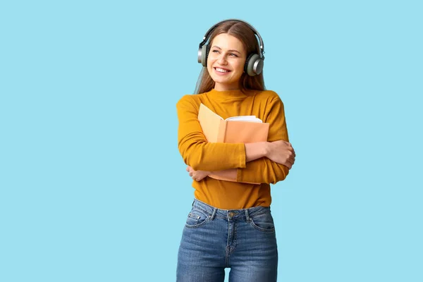 Young woman listening to audiobook on color background — Stock Photo, Image