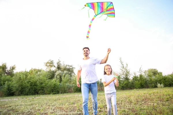 Young man with little daughter flying kite outdoors — Stock Photo, Image