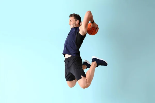 Springender Basketballspieler auf farbigem Hintergrund — Stockfoto