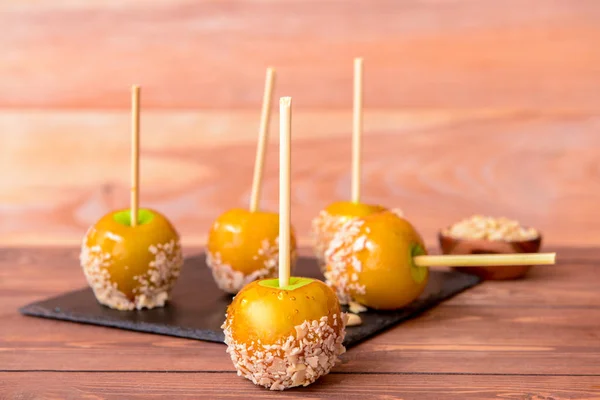 Tasty candy apples on wooden table — Stock Photo, Image