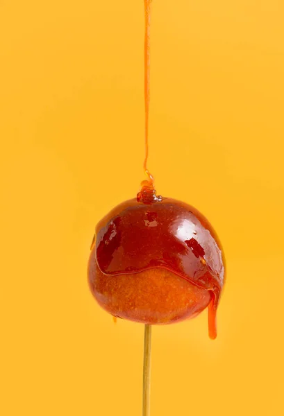 Pouring of hot caramel onto fresh apple against color background — Stock Photo, Image