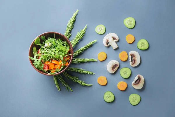 Bowl with tasty arugula salad on grey background — Stock Photo, Image