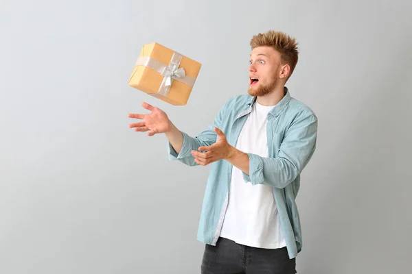 Genç adam ışık arka planda hediye kutusu yakalamak — Stok fotoğraf