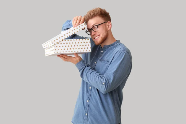 Curious man opening gift box on light background — Stock Photo, Image