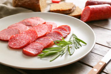 Ahşap masa üzerinde farklı füme sosis dilimleri ile Plaka