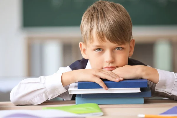 Cute little pupil with books in classroom — Stock Photo, Image