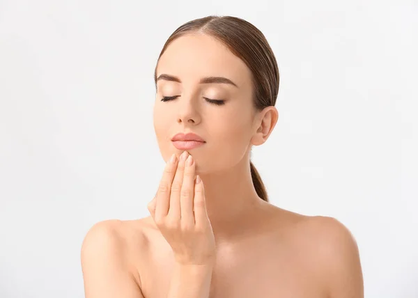 Mooie vrouw masserende haar gezicht tegen witte achtergrond — Stockfoto