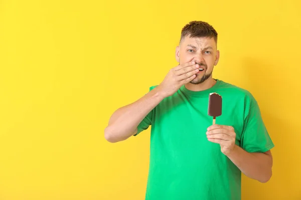 Homem com dentes sensíveis e sorvete frio no fundo de cor — Fotografia de Stock