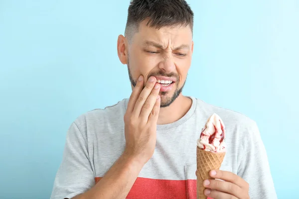 Man with sensitive teeth and cold ice-cream on color background — Stock Photo, Image