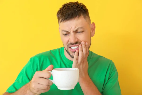 Man med känsliga tänder och hett kaffe på färg bakgrund — Stockfoto