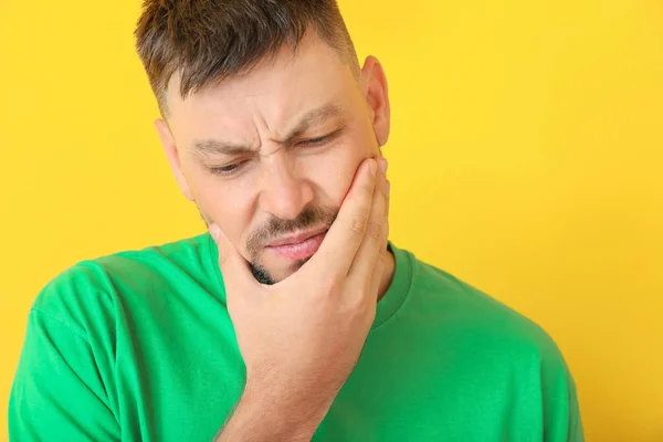 Man som lider av tandvärk mot färg bakgrund — Stockfoto