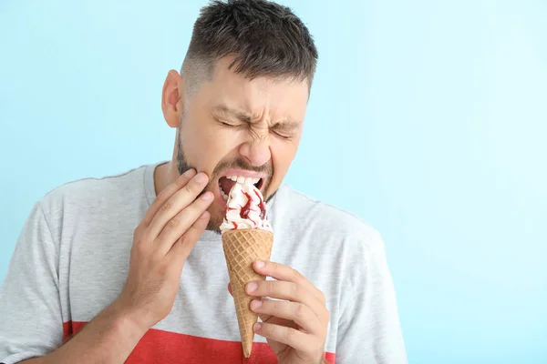 Man with sensitive teeth and cold ice-cream on color background — Stock Photo, Image