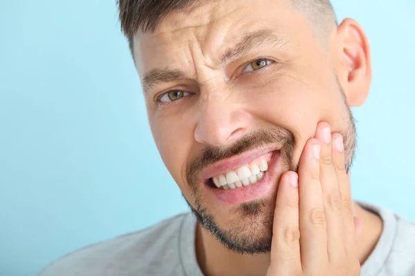 Homme souffrant de maux de dents sur fond de couleur, gros plan — Photo