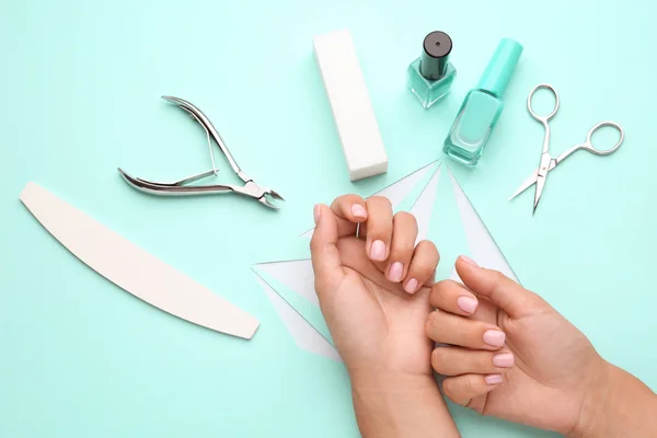 Manos femeninas con suministros para manicura sobre fondo de color — Foto de Stock