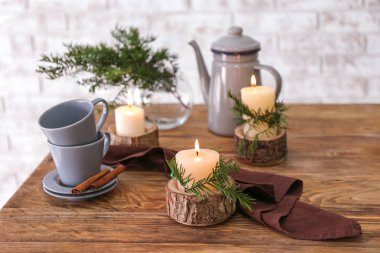 Kahve demliği, bardaklar ve masada yanan mumlar