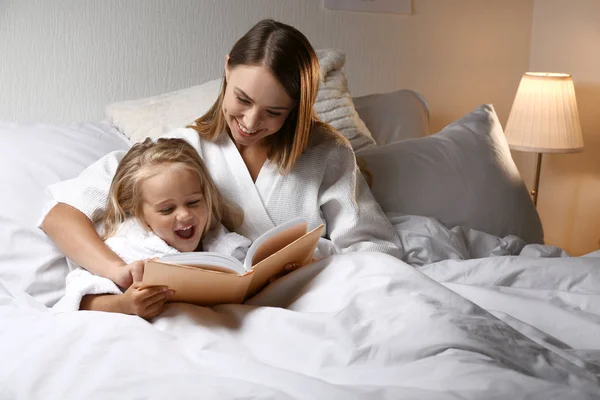 ベッドで本を読んで彼女の小さな娘と幸せな女性 — ストック写真
