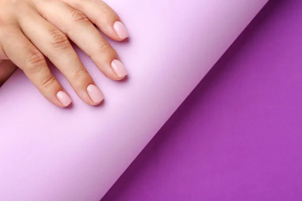 Жіноча рука з красивим манікюром і папером на кольоровому фоні — стокове фото