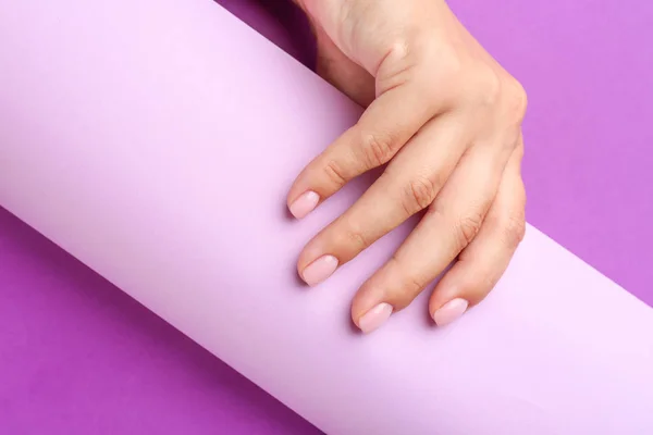 Female hand with beautiful manicure and paper on color background — Stock Photo, Image