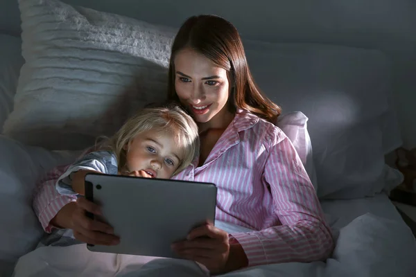 Šťastná žena s dcerkou s tabletovým počítačem v posteli — Stock fotografie