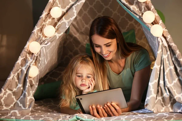 Happy woman and her little daughter with tablet computer in hovel at home — Stock Photo, Image