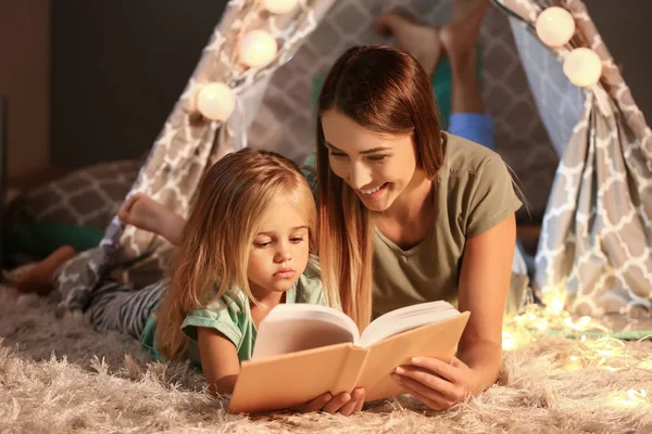 Mother and her little daughter reading book in evening — Stock Photo, Image