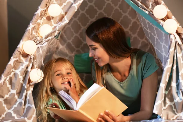 Happy woman with her little daughter reading book in hovel at home — Stock Photo, Image