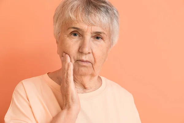 Donna anziana che soffre di mal di denti contro lo sfondo di colore — Foto Stock