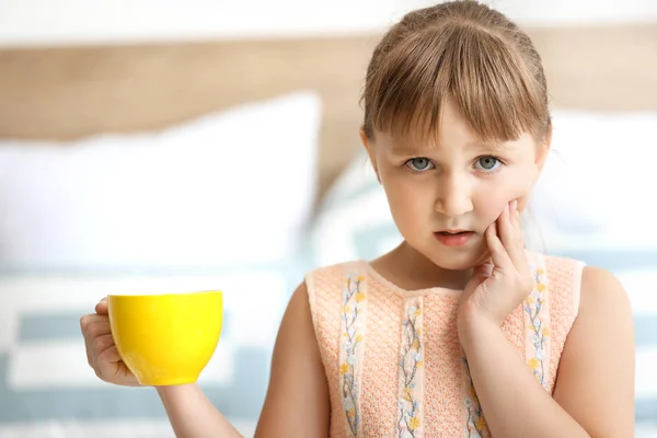 Little girl with sensitive teeth and cup of tea at home — Stock Photo, Image