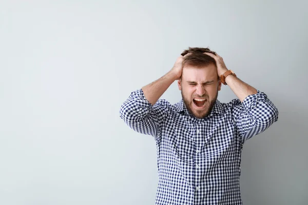Stressed young man on light background — Stock Photo, Image