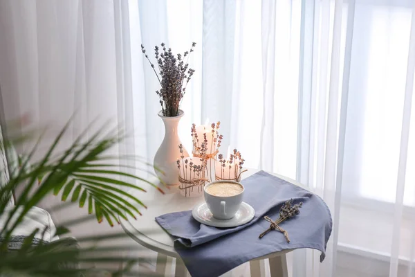 Cup of coffee, burning candles and lavender on table in room — Stock Photo, Image