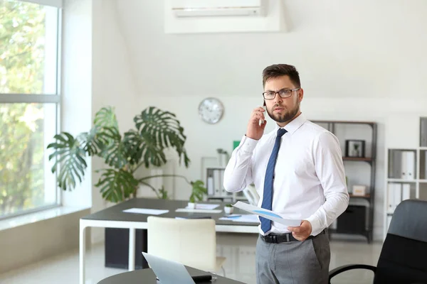 Portrait of businessman talking by phone in office — Stock Photo, Image