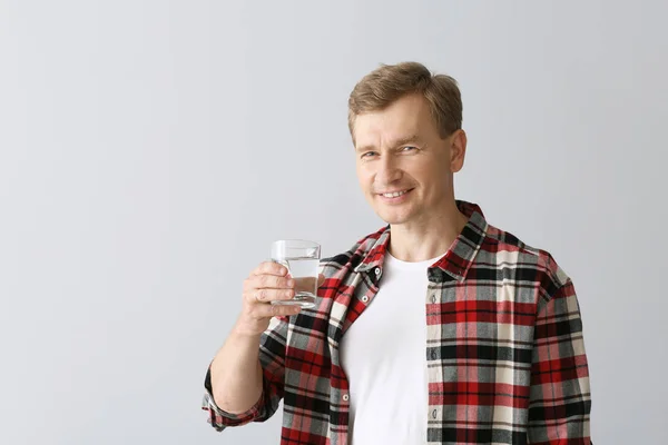 Portrait of handsome man drinking water on light background — Stock Photo, Image