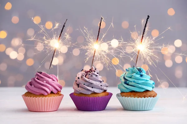 stock image Tasty Birthday cupcakes on table against defocused lights