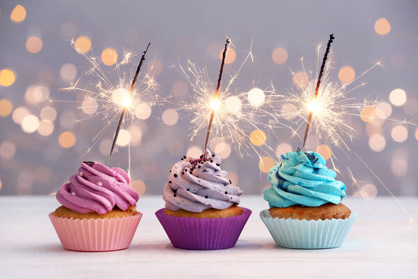 Tasty Birthday cupcakes on table against defocused lights