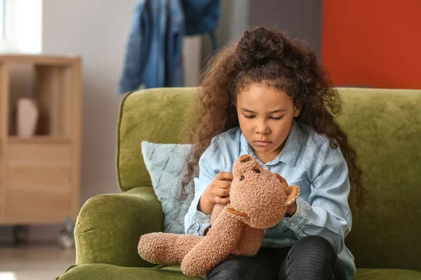 African-American girl with toy bear at home