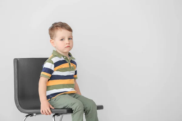 Niño pequeño con trastorno autista sentado en silla sobre fondo claro —  Fotos de Stock