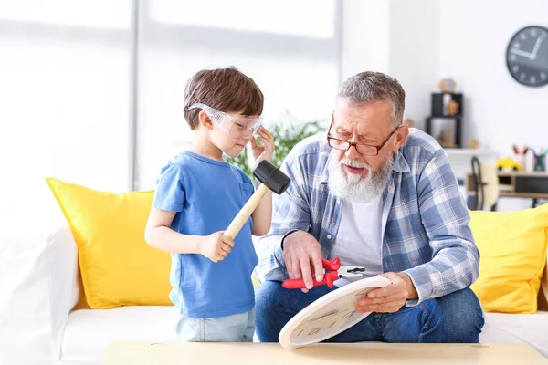 Grandfather teaching little boy to repair clock at home — Stock Photo, Image